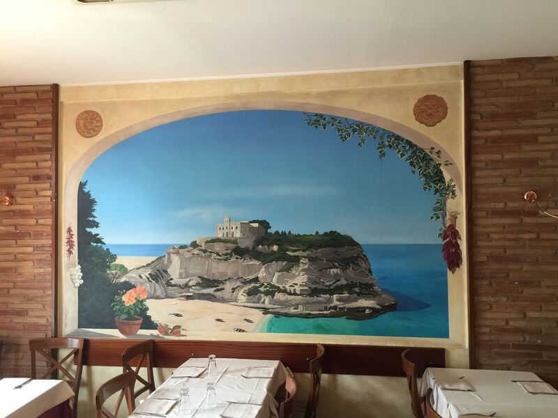 La sala di Carmen 2 con il murale di Tropea sui mattoni a vista